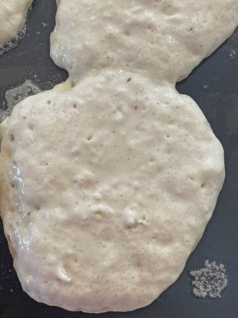 Pancakes bubbling on a grill.